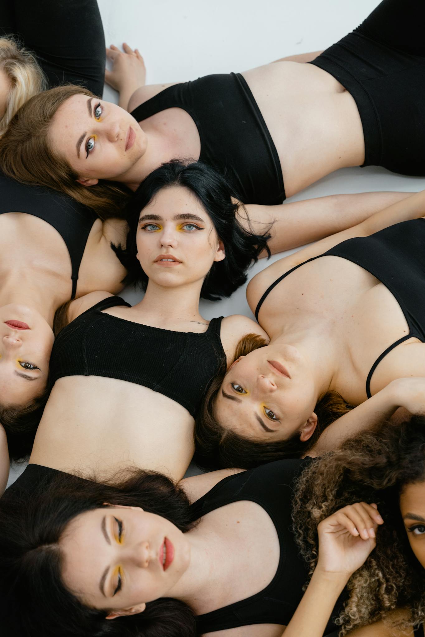 A group of women lying down in stylish black outfits, expressing unity and diversity.